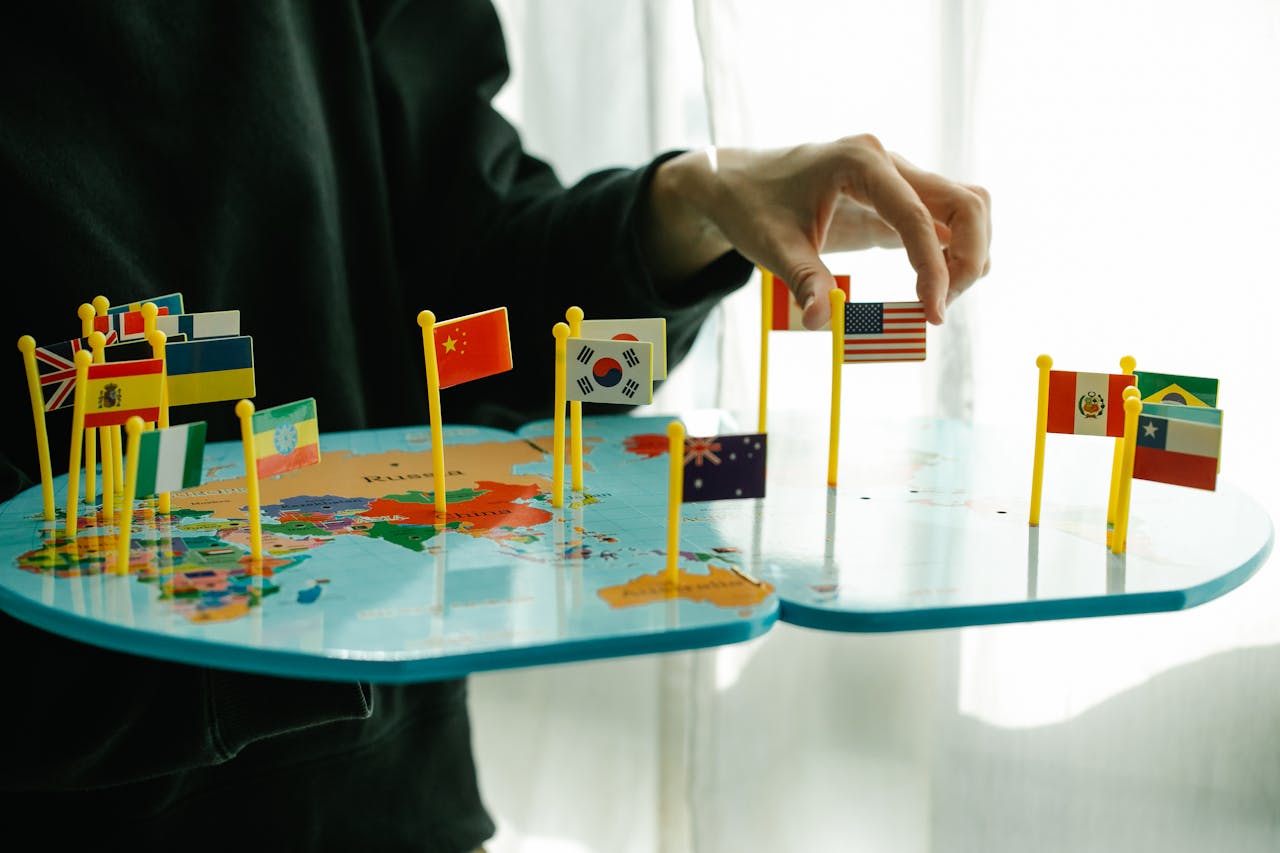 home-services-02 Hand arranging flags on a world map, signifying global diversity.