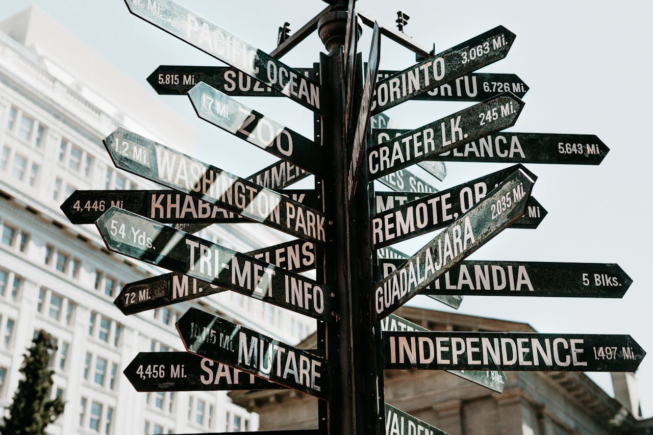 home-services-03 Close-up of a directional signpost with city names and distances in an urban setting.